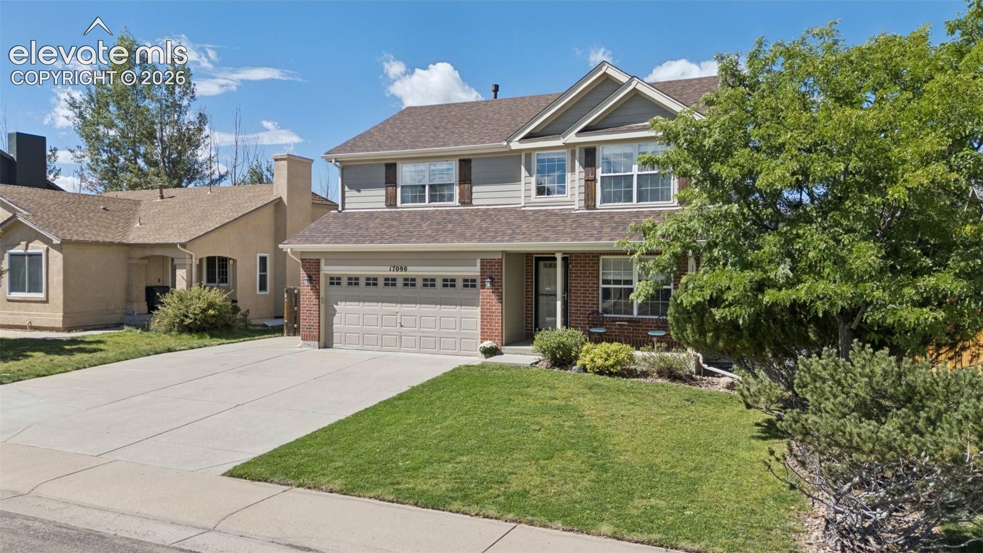 Two-story residence featuring a brick and siding exterior, an attached two-car garage, and a concrete driveway
