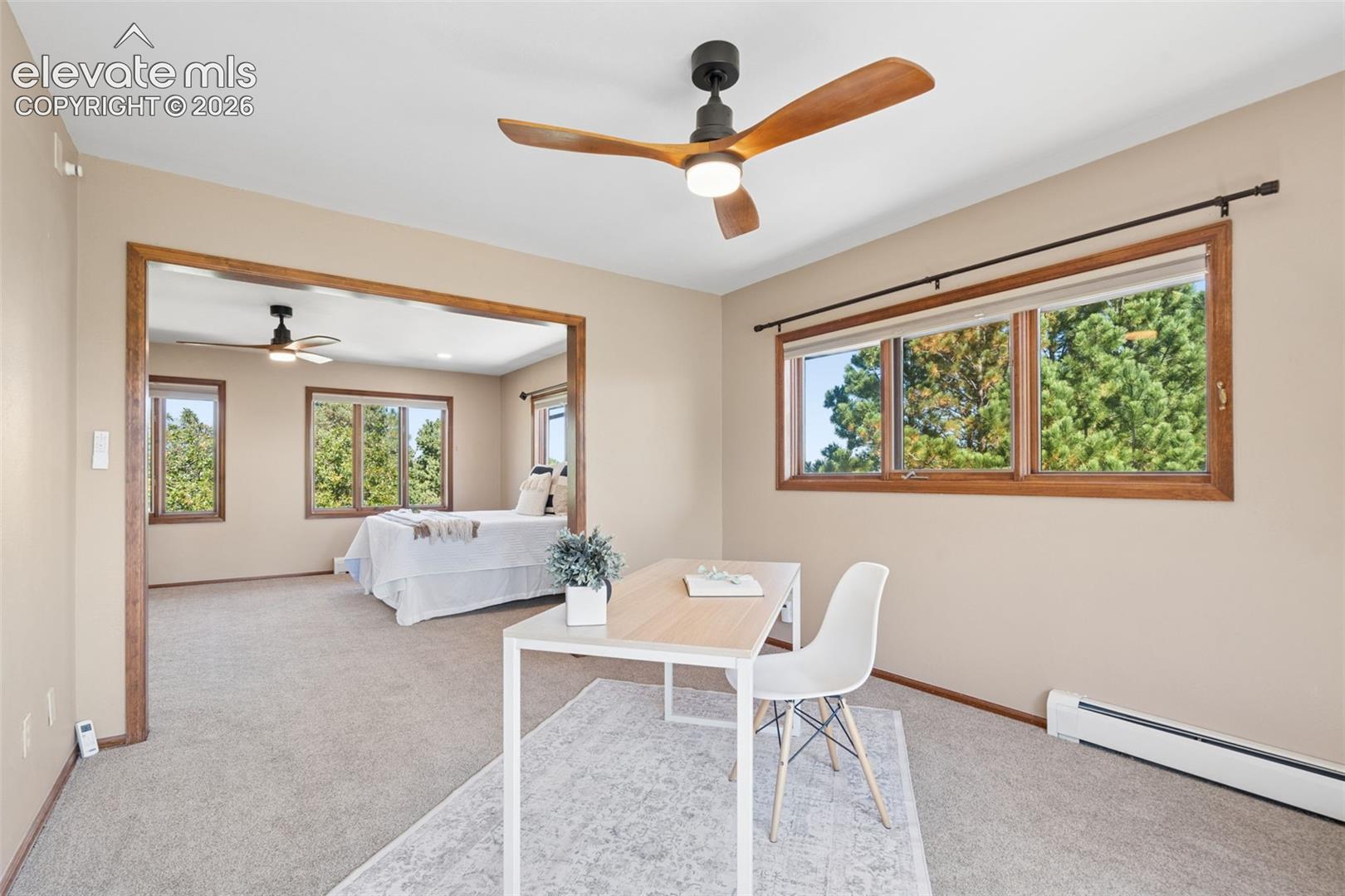 Carpeted interior with wood-trimmed windows, a modern ceiling fan, and a wide cased opening
