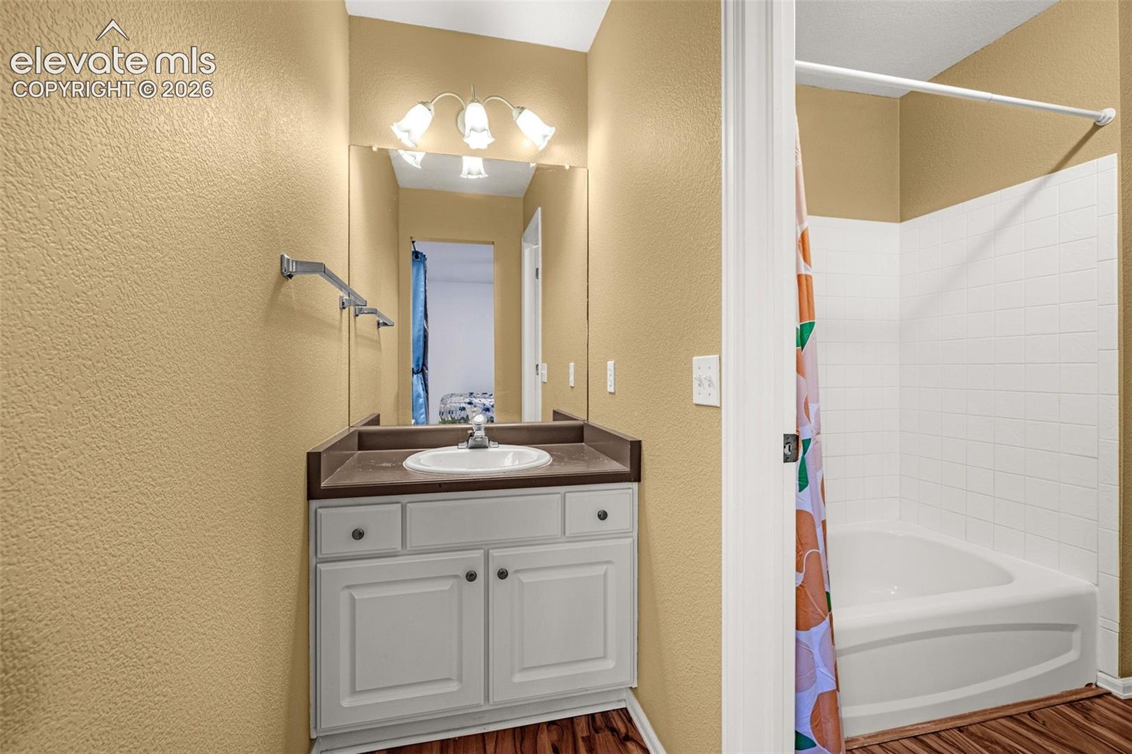 Vanity with an integrated sink, polished chrome faucet, and a large mirror with overhead lighting