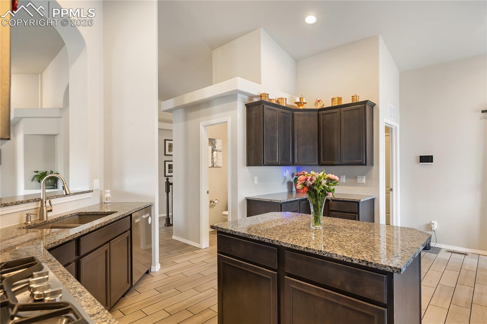 Kitchen featuring a central island, dark wood cabinetry, granite countertops, and stainless steel appliances