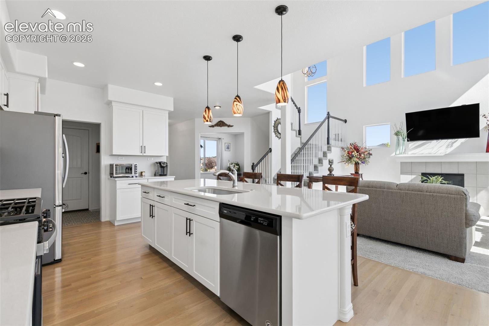 Kitchen island with a built-in stainless steel dishwasher, a single basin sink, and pendant lighting