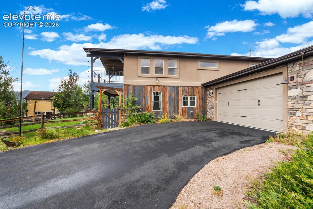 Exterior featuring a two-car garage, stone and stucco siding, and a second-story balcony