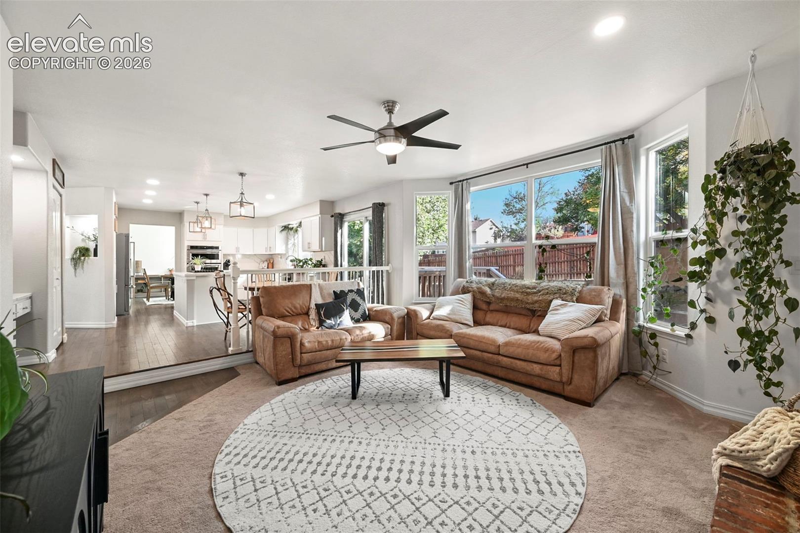 Recessed lighting, ceiling fan, wood-finish flooring, white cabinetry, and large windows