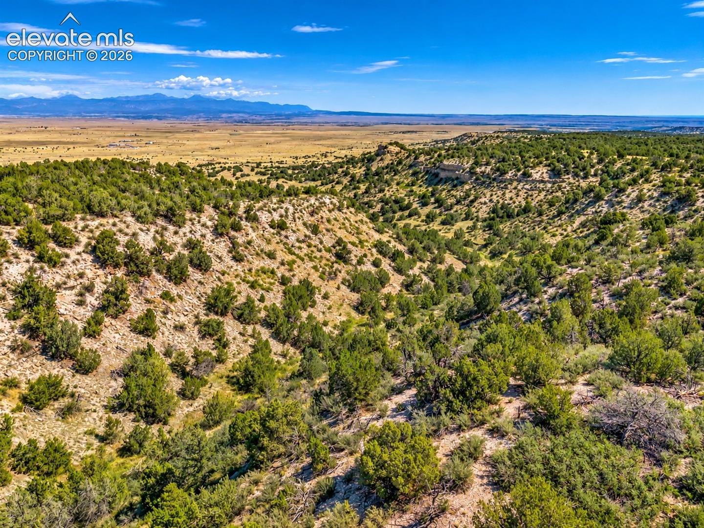 Incredible aerial perspective showcasing the property's rugged terrain, dramatic rock formations, and steep natural ravines overlooking the expansive Southern Colorado landscape.

