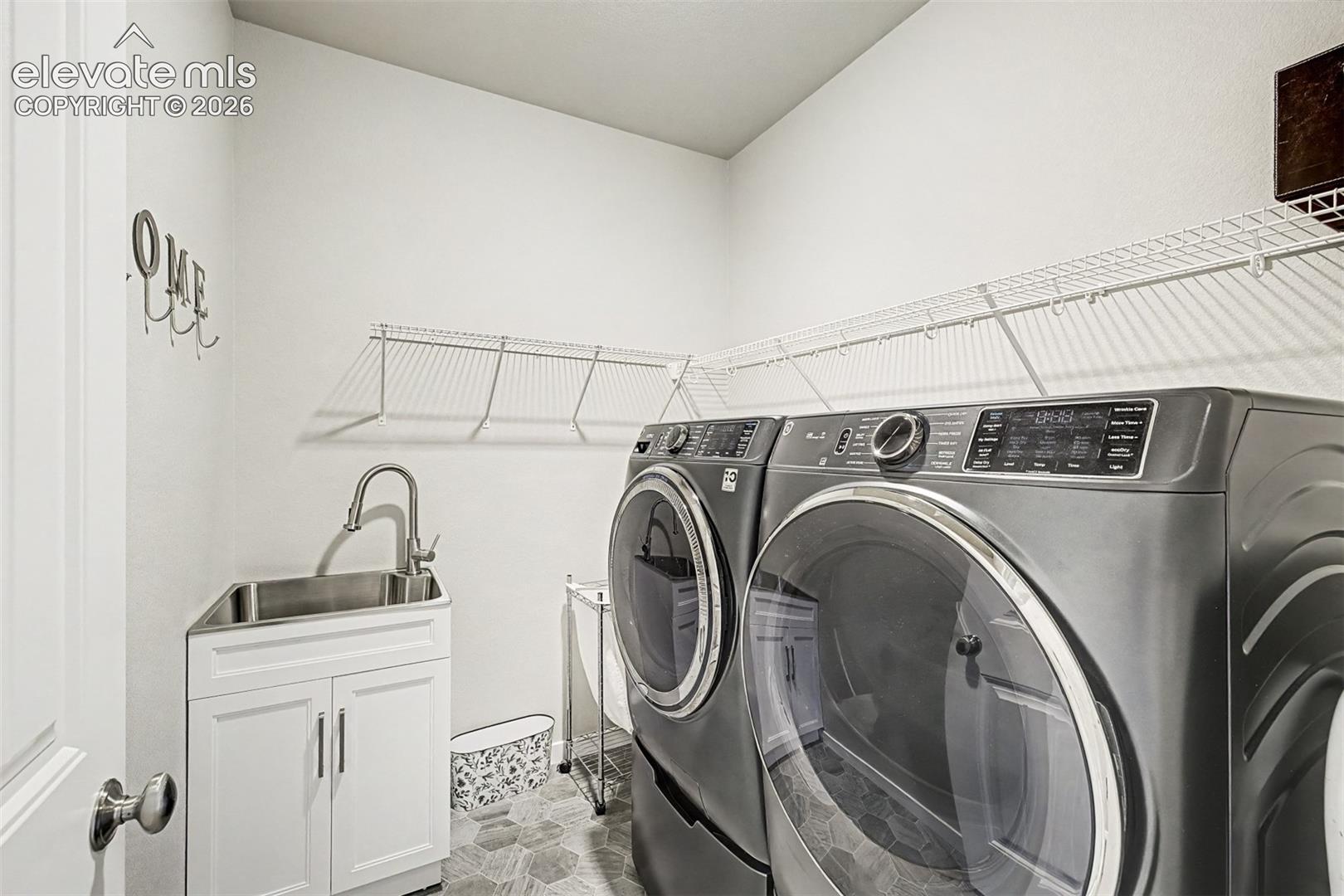 Convenient main-level laundry room with cabinetry and utility sink keeps everyday tasks organized and easily accessible.