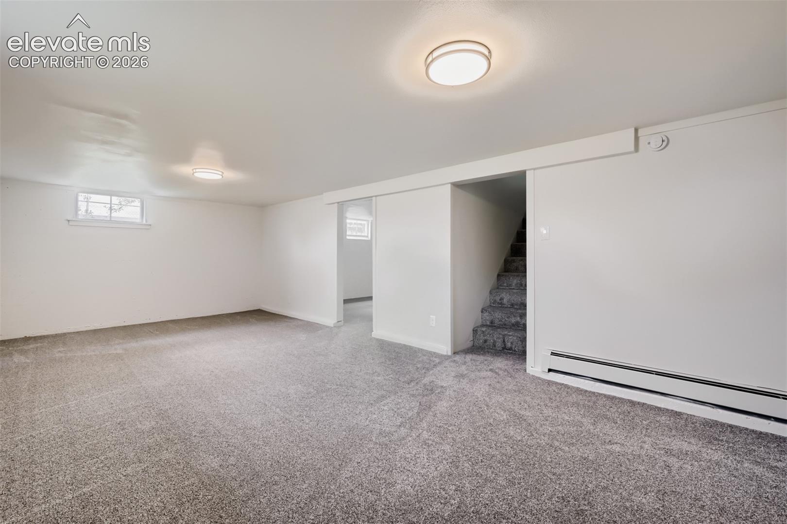 Spacious room with gray carpet, white walls, flush mount lighting, and a small window