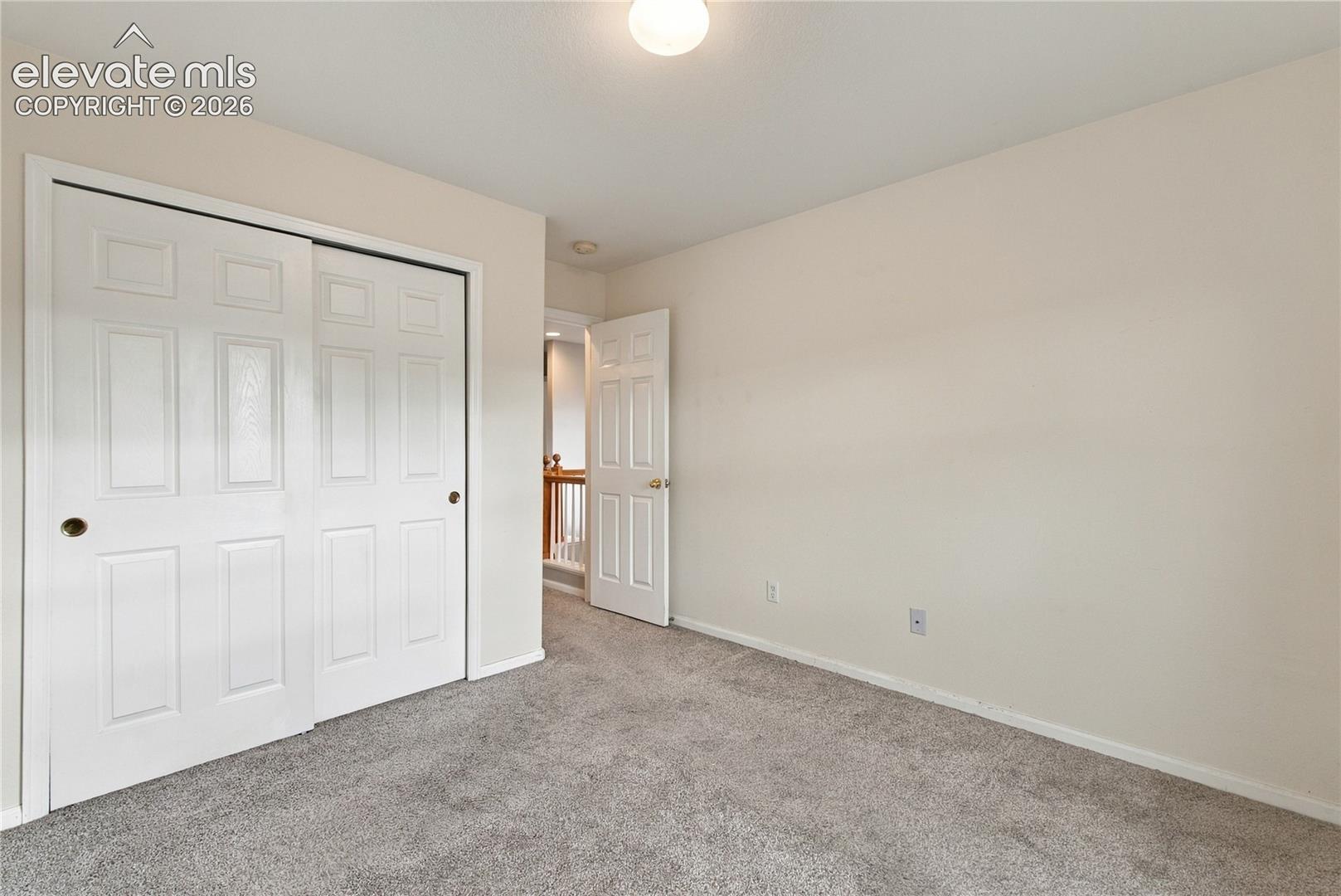 Neutral-toned wall paint, carpeted flooring, sliding-door closet, and interior six-panel door