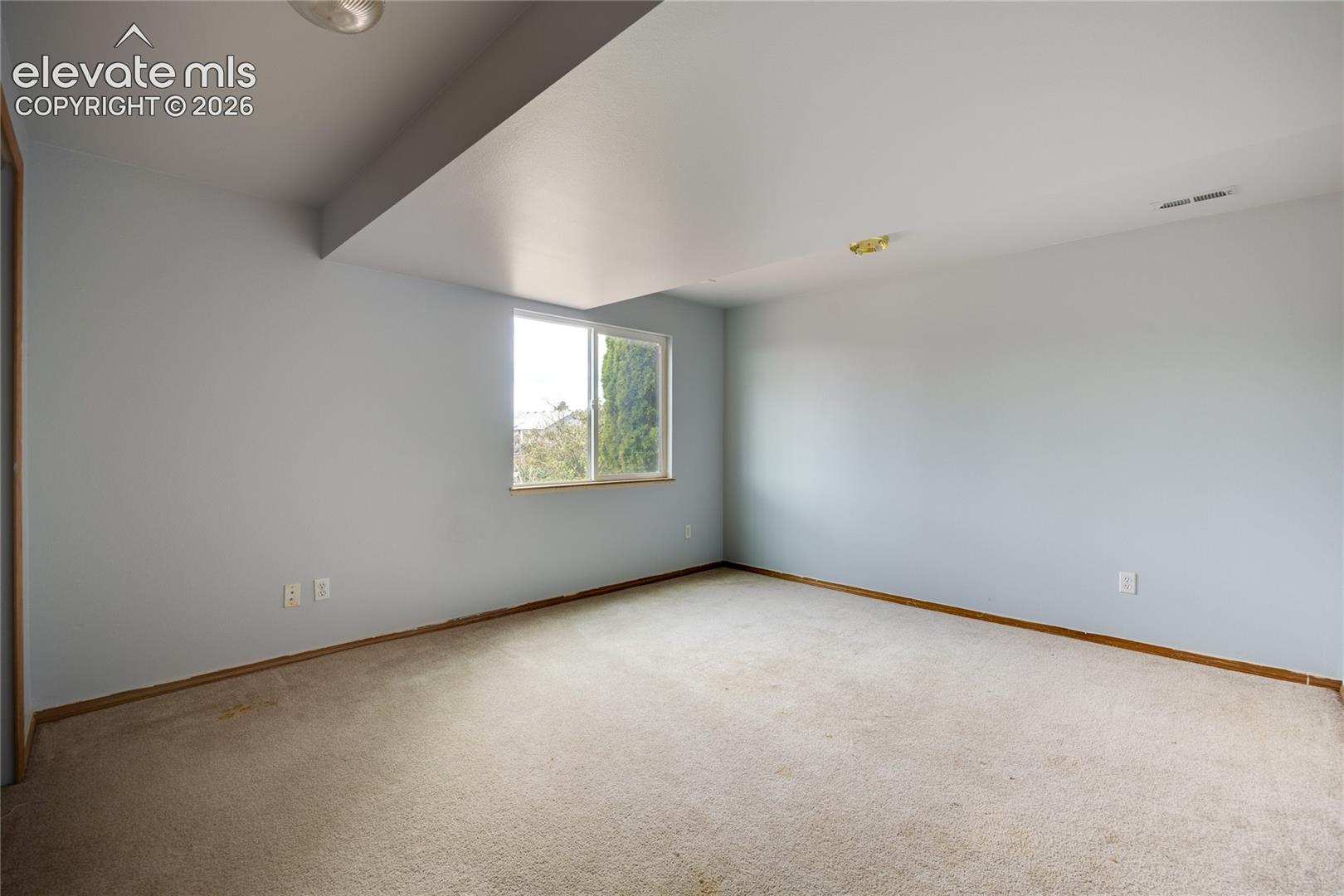 Expansive room with neutral carpeting and light-toned walls