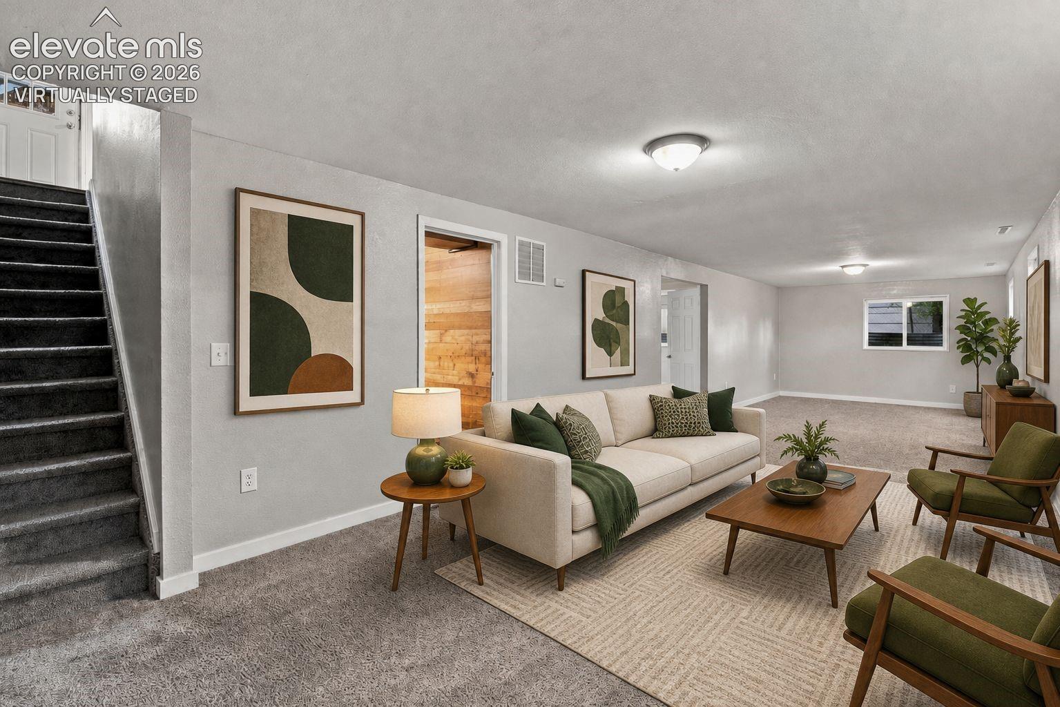 Huge basement area with carpeted flooring throughout, recessed window, white trim, and staircase that goes into the kitchen/dining area *virtually staged