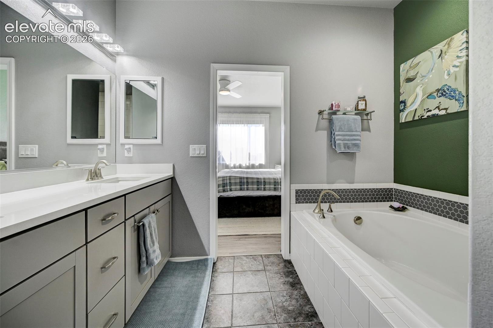 Bathroom featuring a white built-in bathtub with subway tile surround and a dark hexagonal tile accent
