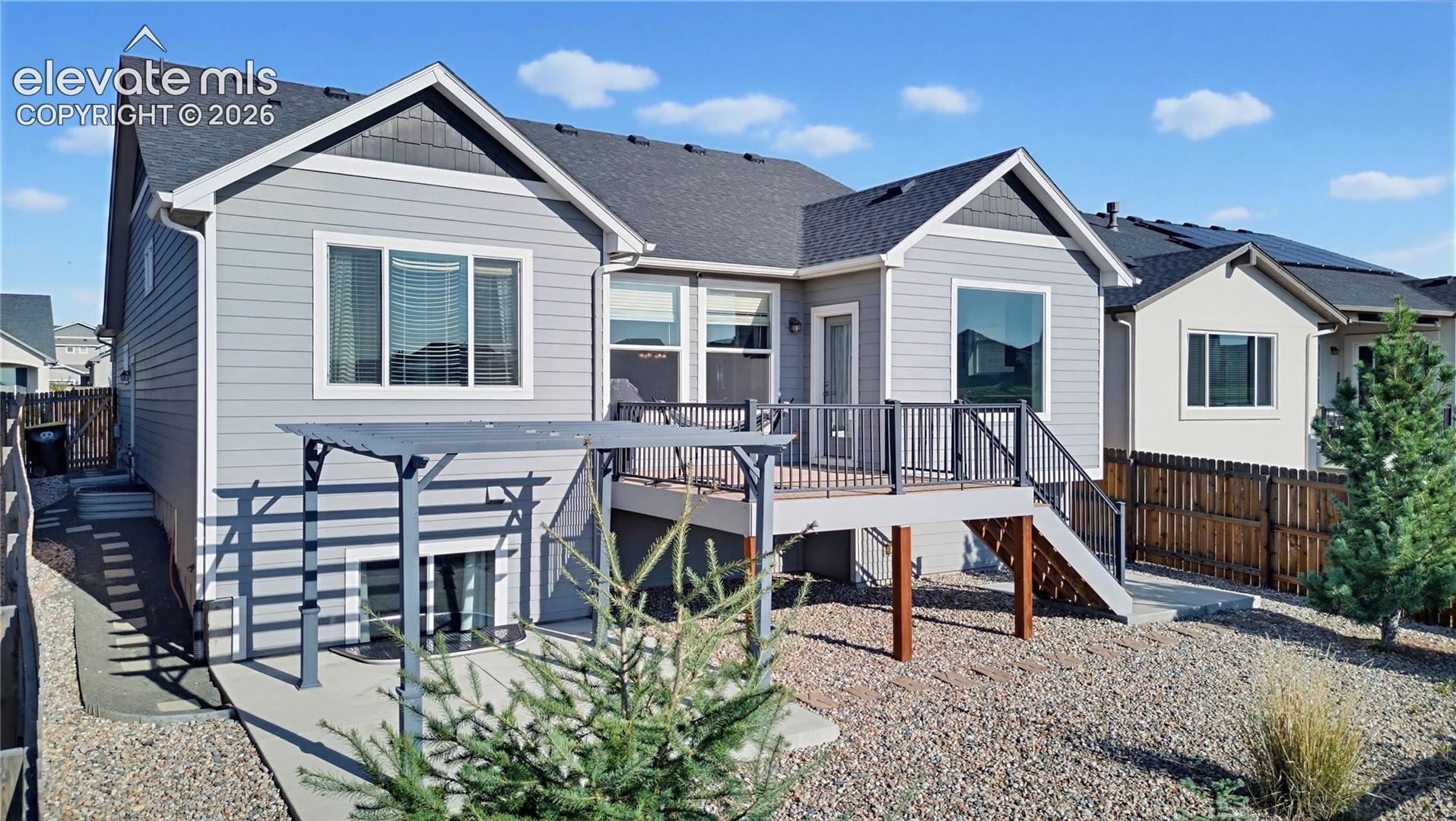 Rear exterior featuring horizontal lap siding, a composite deck with metal railings, a concrete patio, and a metal-framed pergola