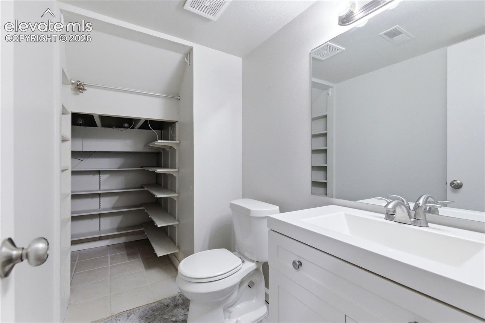 Bathroom featuring a white vanity with integrated sink, chrome faucet, and a wall-mounted mirror