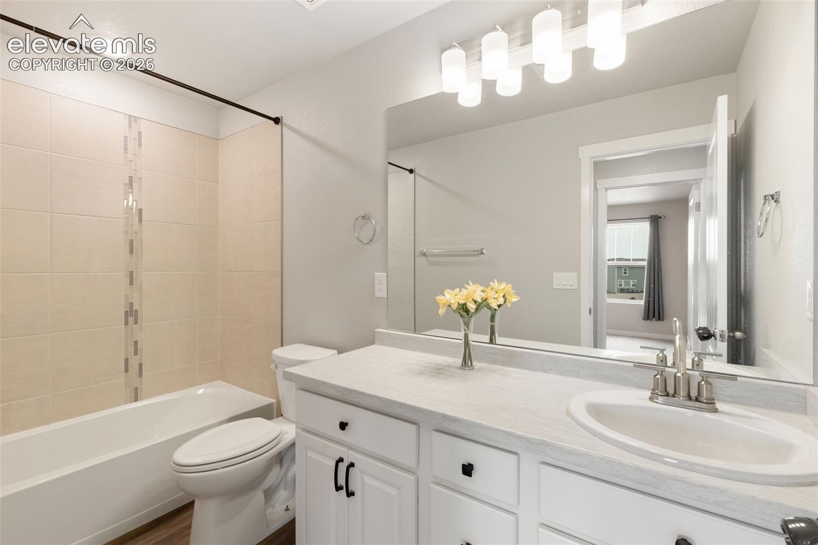 Bathroom featuring a single vanity with white cabinetry, a built-in sink, and a light-colored countertop