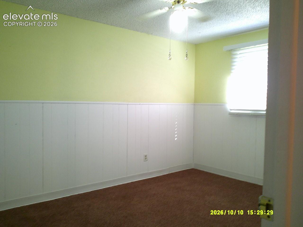 Carpeted room featuring white wainscoting and a ceiling fan