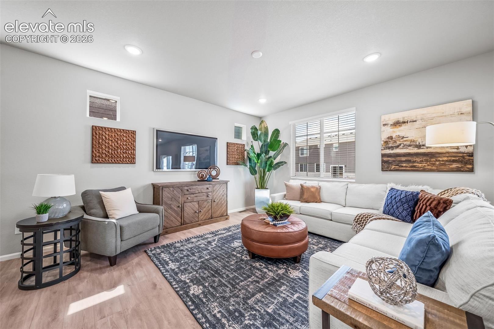 Recessed lighting illuminates the open living space, featuring wood-finish flooring and multiple windows with blinds
*photos of a model home*