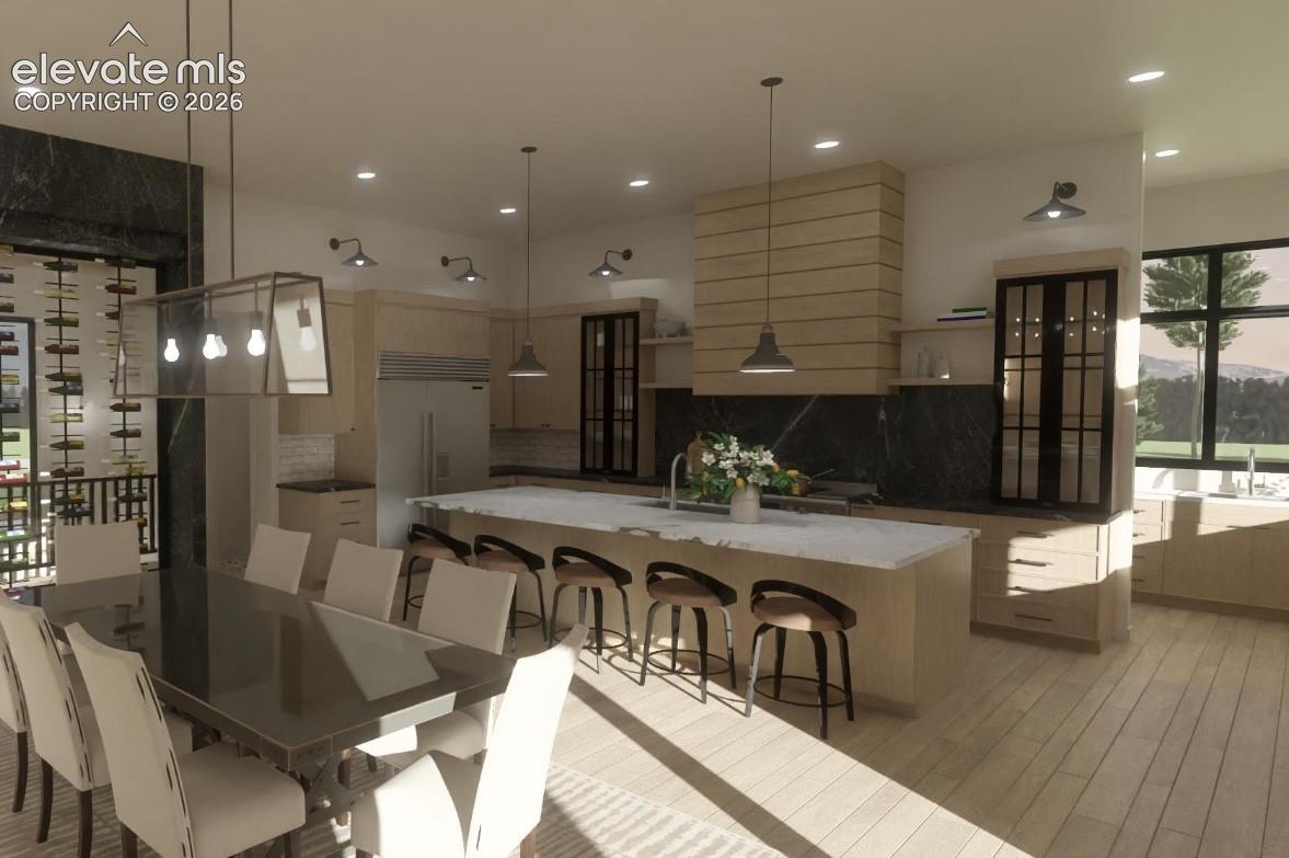 Open concept living space featuring a built-in wine rack wall, large kitchen island with counter seating, integrated stainless steel refrigerator, and wood-finish flooring