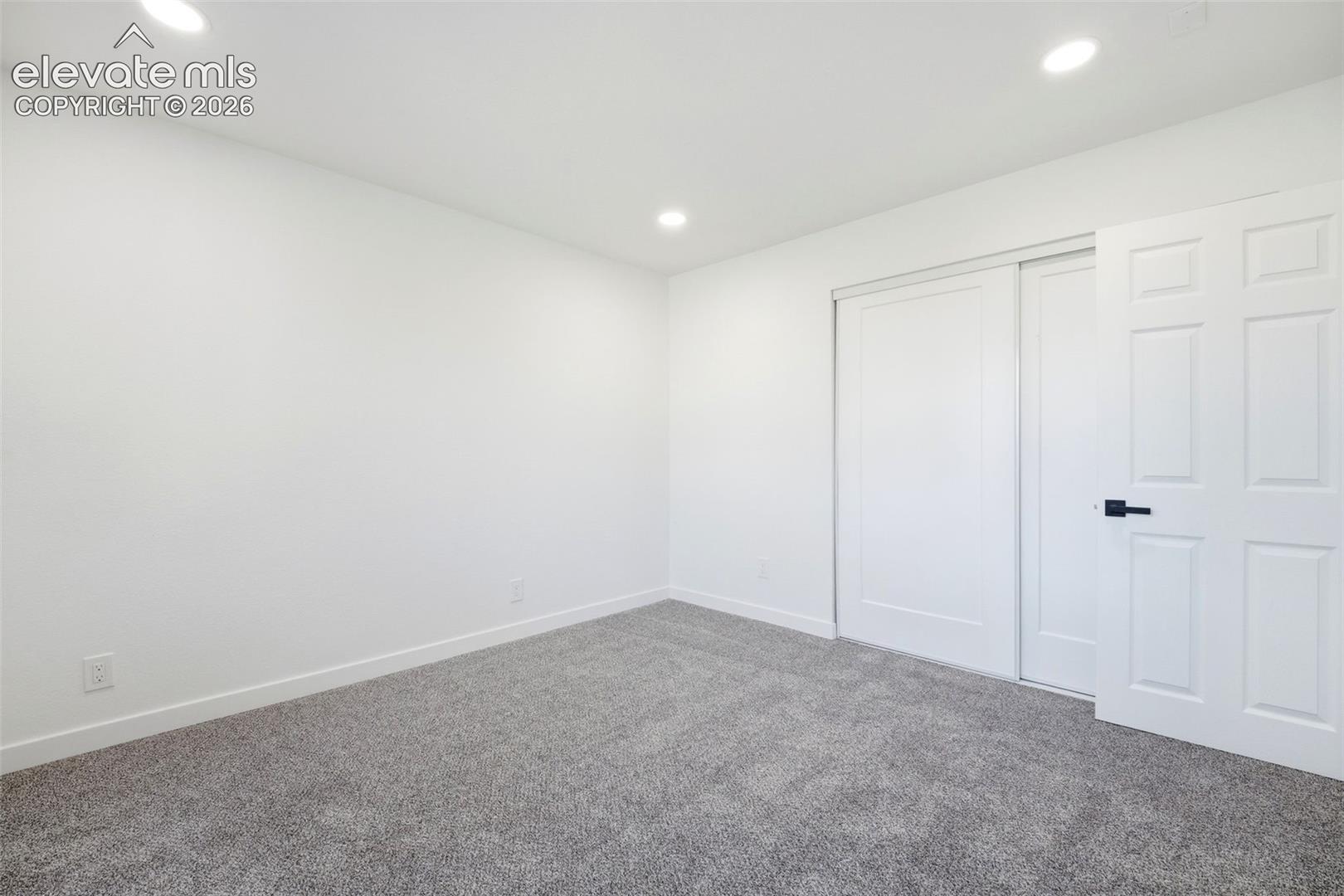 Interior room featuring recessed lighting, light gray carpeting, white baseboards, and a white sliding closet door