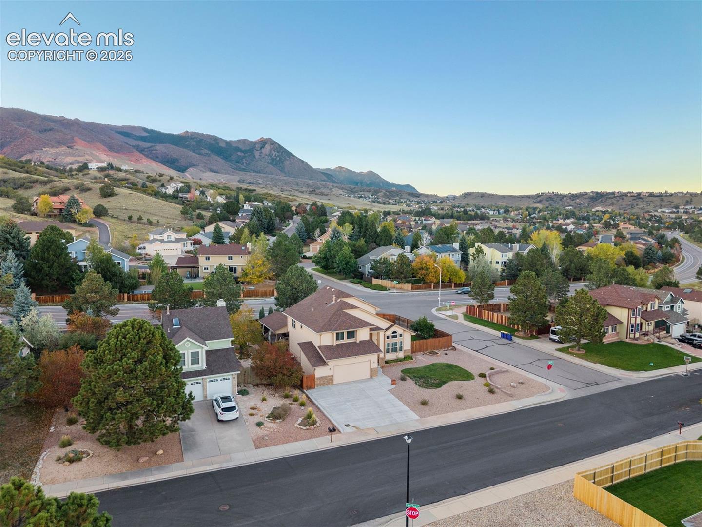 Aerial perspective of a multi-level suburban residence featuring a concrete driveway, two-car garage, and desert-inspired landscaping against a prominent mountain backdrop