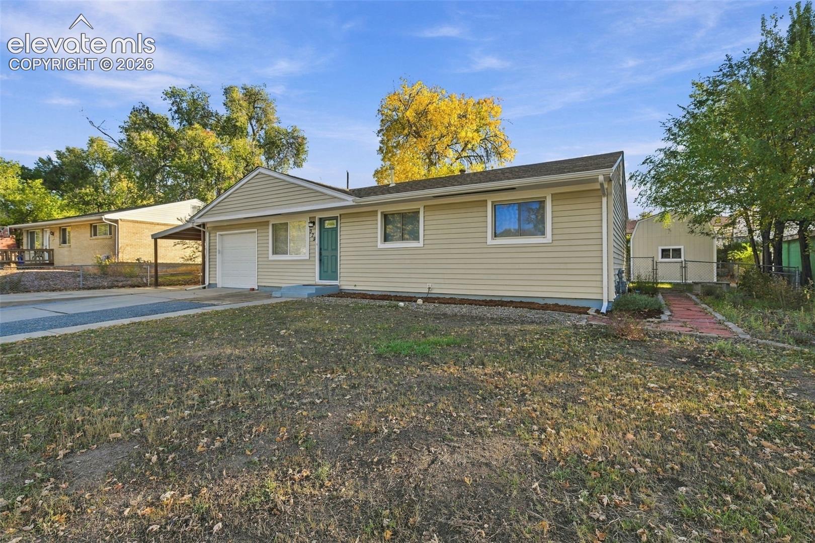 Ranch-style residence featuring horizontal vinyl siding, a single-car garage, an attached carport, and a detached storage structure