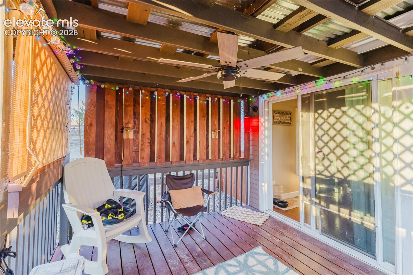 Covered exterior deck with wood-finish flooring, exposed beam ceiling, and a ceiling fan