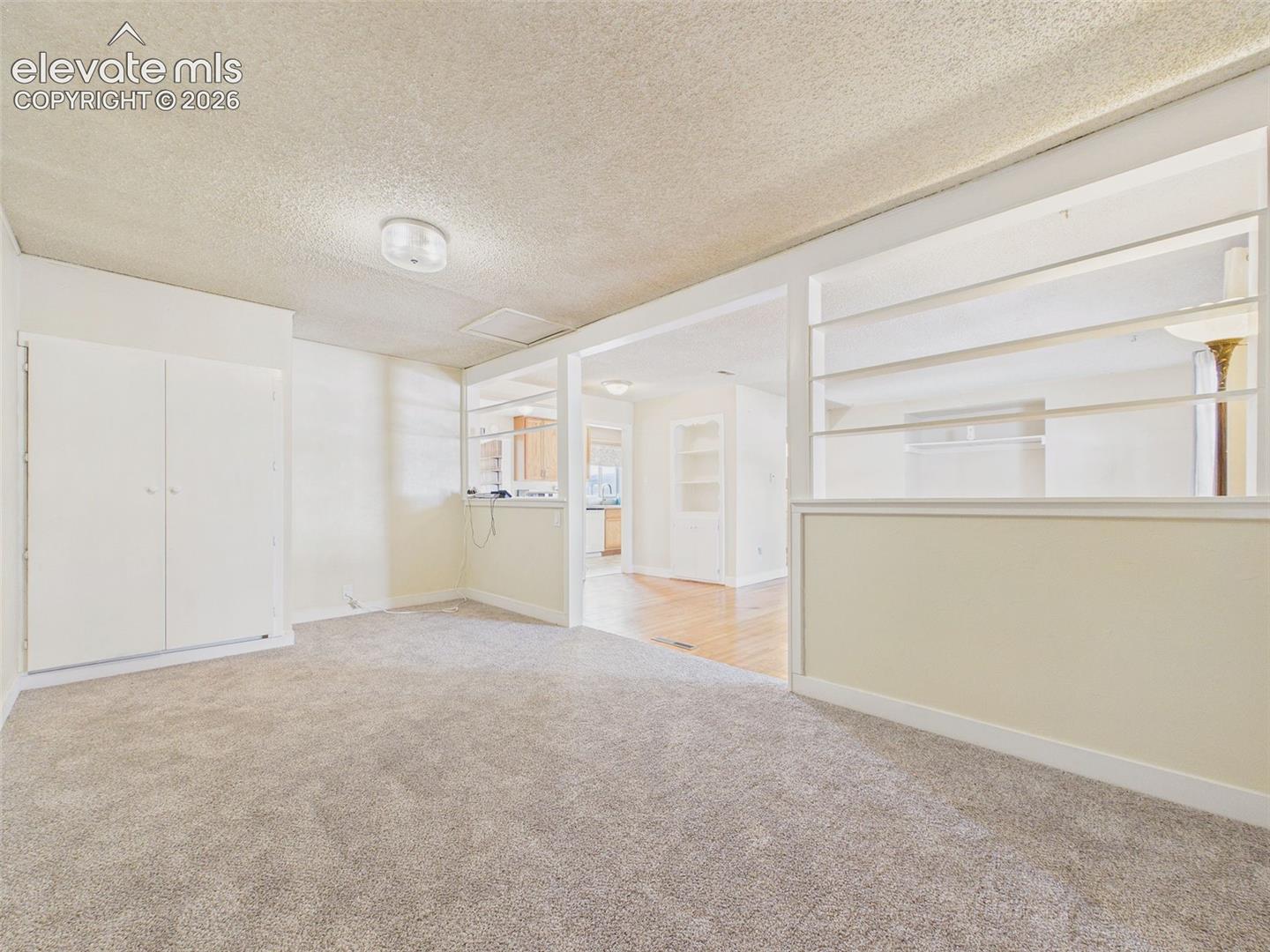 Additional view of the carpeted bonus room highlighting the open connection to the living area and distinctive architectural shelving.