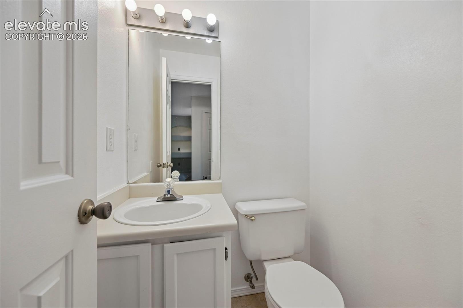 White vanity with an integrated sink and base cabinetry, complemented by a wall-mounted mirror with overhead bar lighting