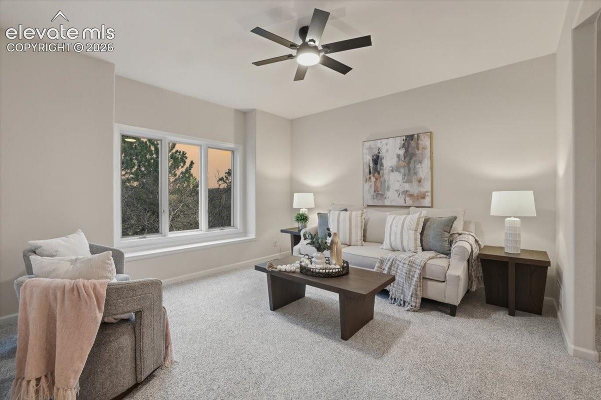 Expansive window with a wide sill, ceiling fan, and carpeted flooring