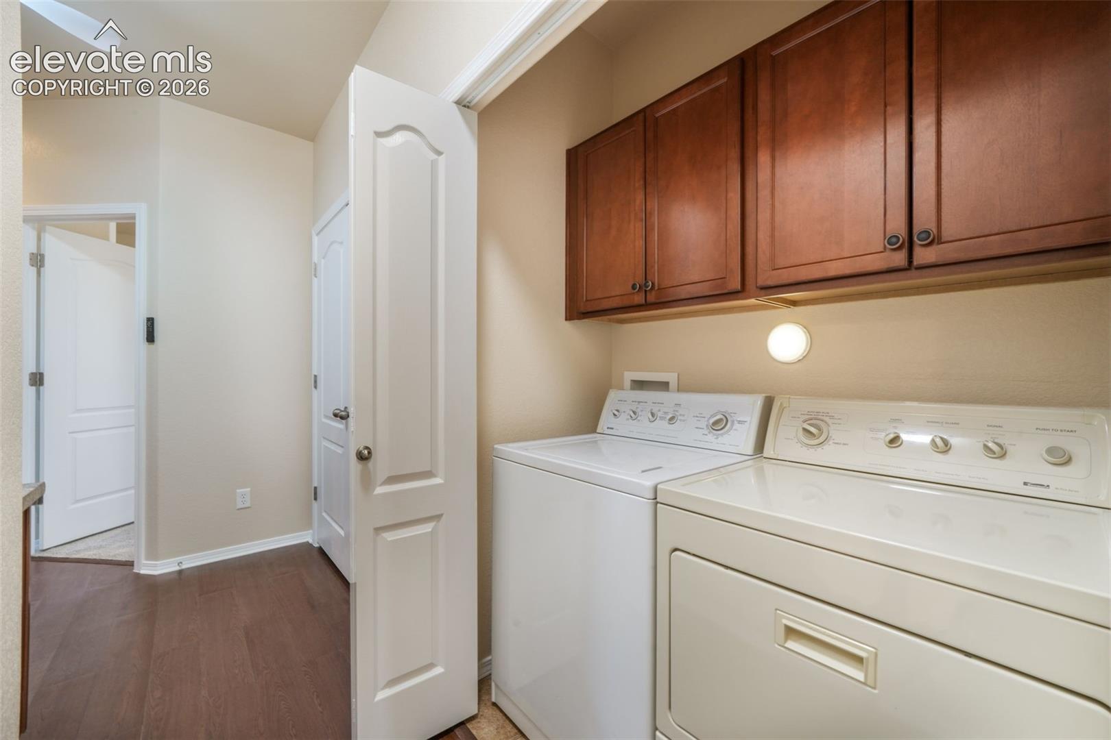 Laundry area featuring dark wood-finish cabinetry, under-cabinet lighting, and wood-finish flooring
