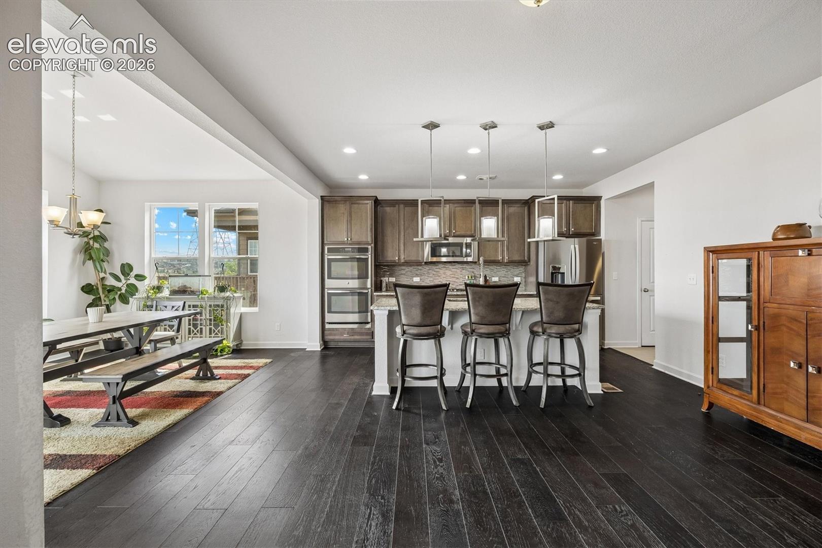 Kitchen featuring an island with pendant lighting, stainless steel appliances, dark wood cabinetry, and a tile backsplash