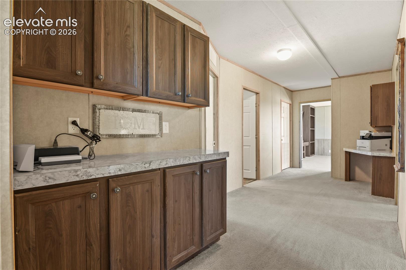 Built-in cabinetry with wood-finish doors, stone-patterned countertops, and dedicated desk alcove with integrated storage