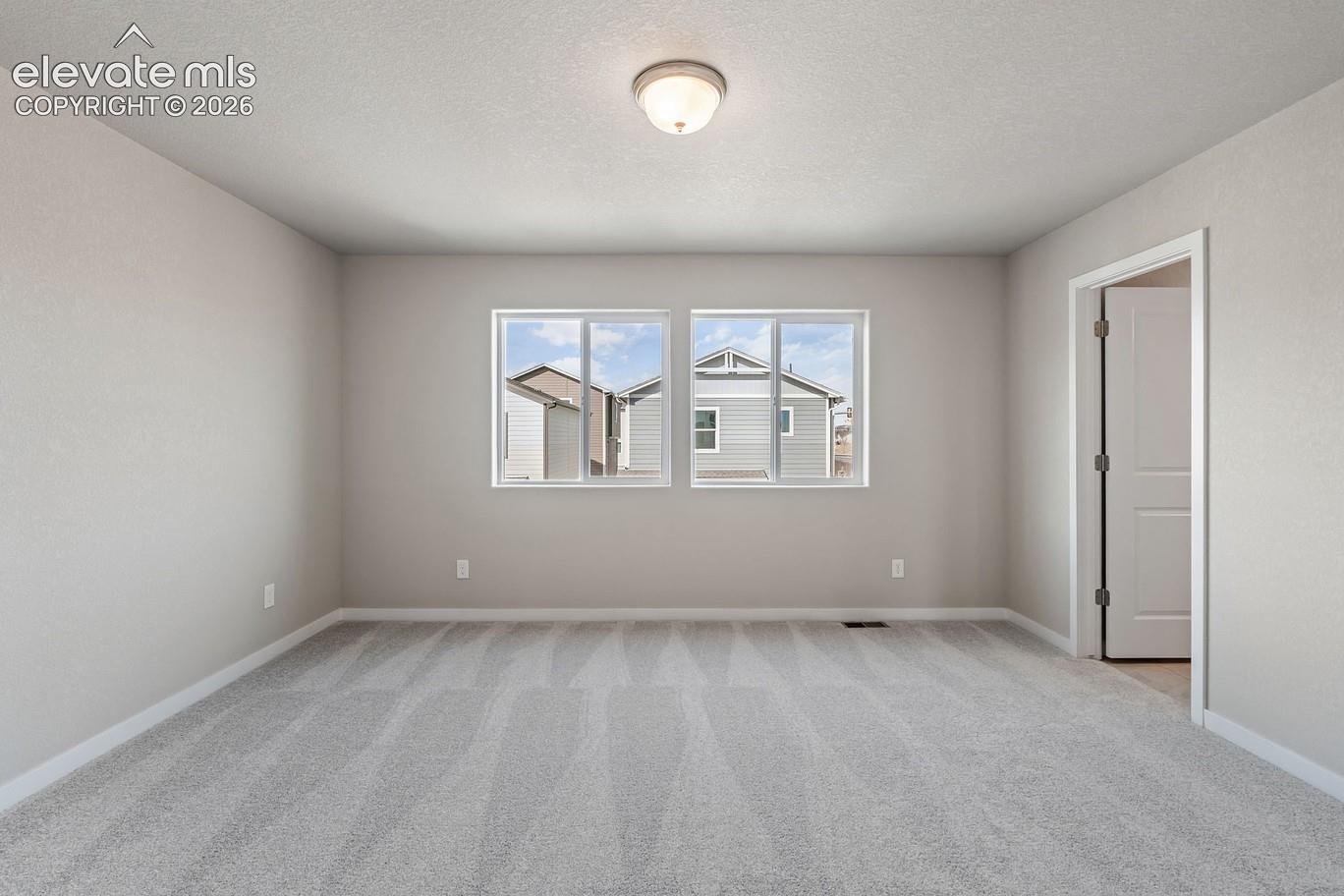 bedroom with three-pane window and neutral walls, ceiling light, and carpeted floor