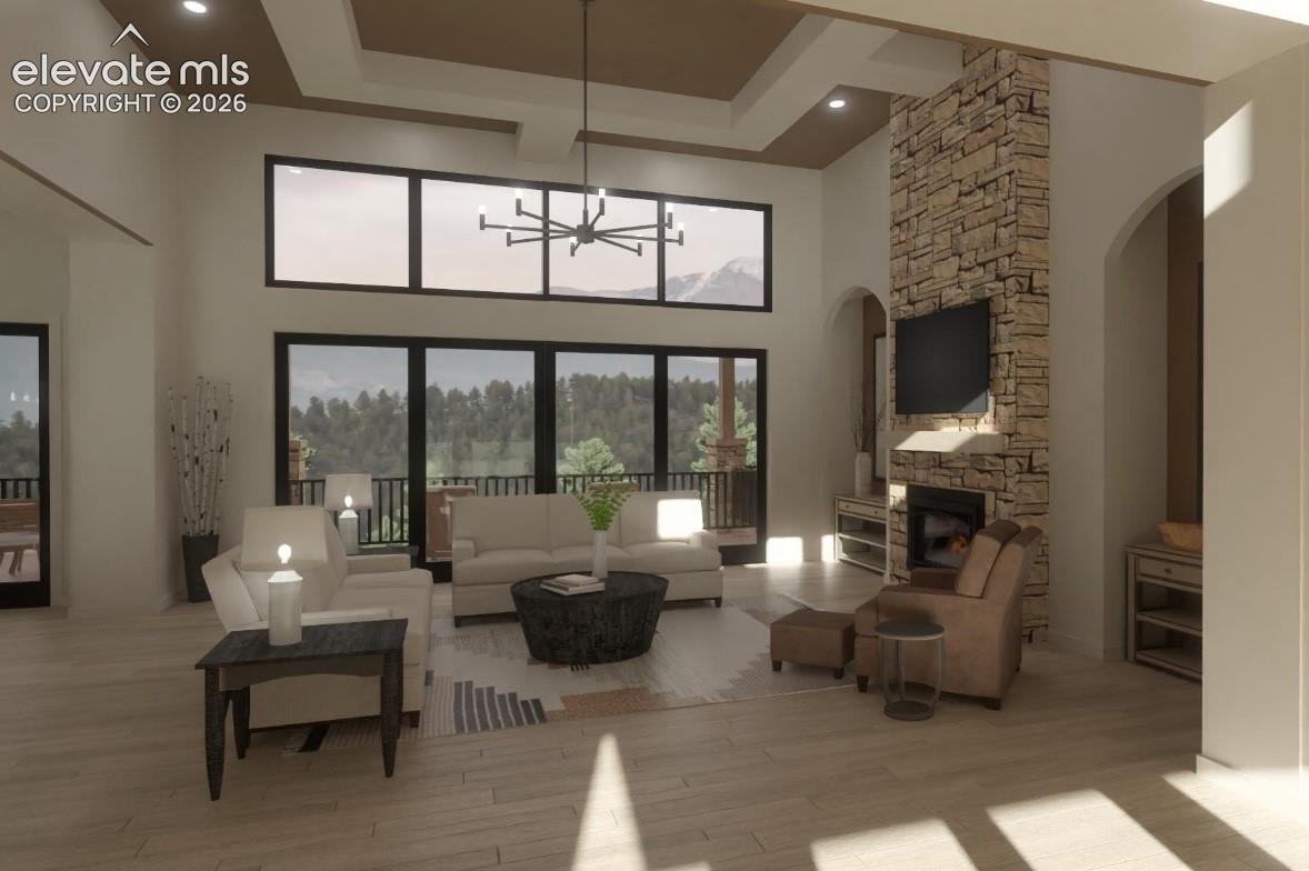 Expansive living space featuring a high vaulted ceiling, stone fireplace, and large windows with transom panels and wrap around deck