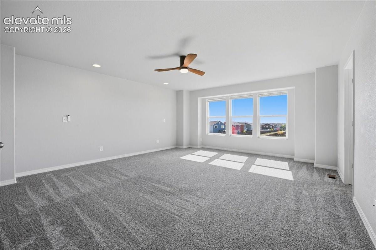 Neutral-toned carpet, three-paneled window configuration, and wood-finish ceiling fan with integrated lighting
