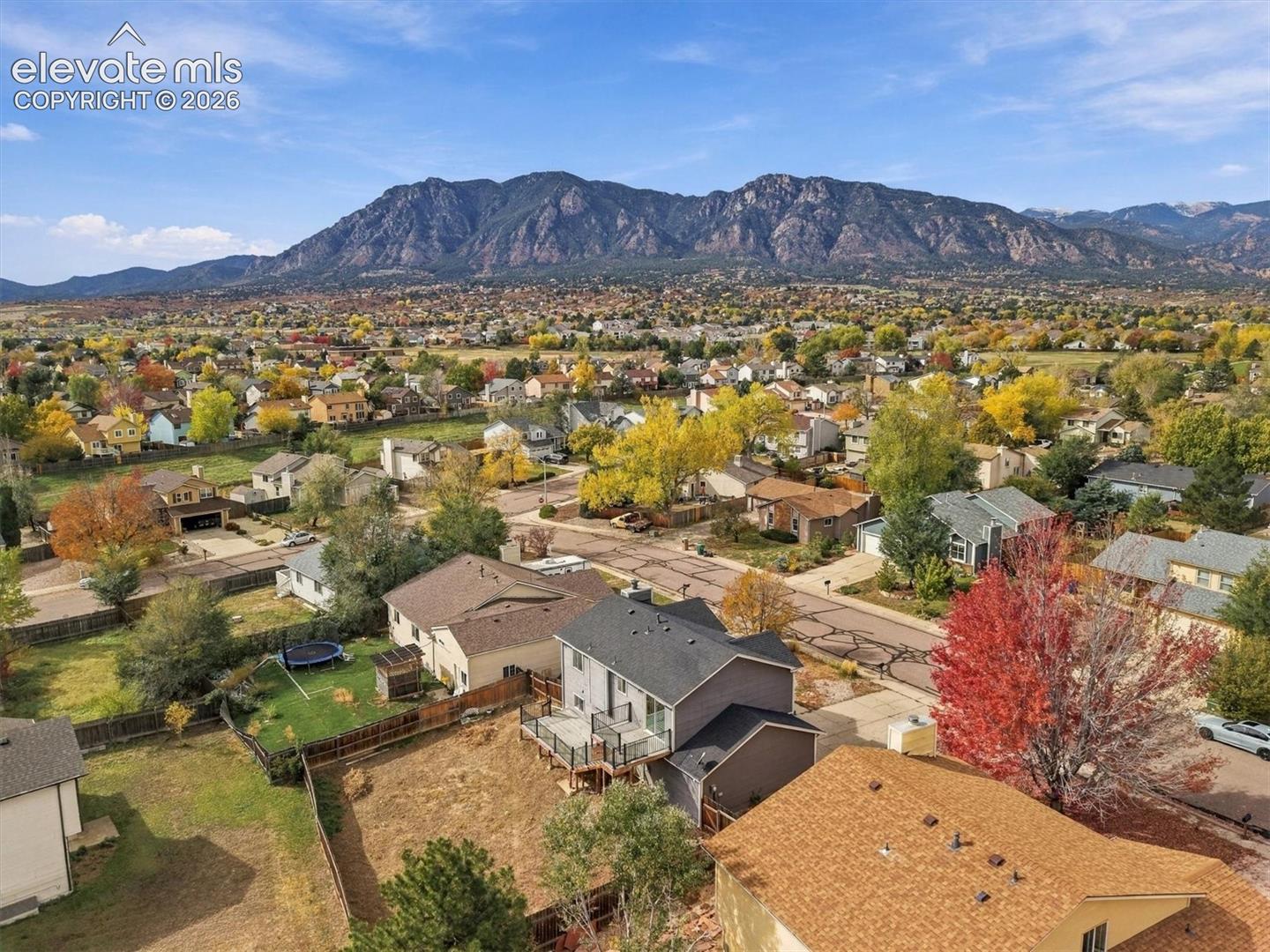 Aerial perspective of property featuring an elevated wooden deck with railings, asphalt shingle roofing, and a prominent mountain range backdrop
