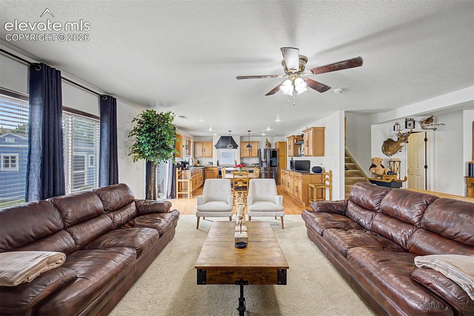 The great room unfolds in impressive fashion, with the living area flowing seamlessly toward the dining space and kitchen beyond, a layout made for gathering and entertaining on any scale.