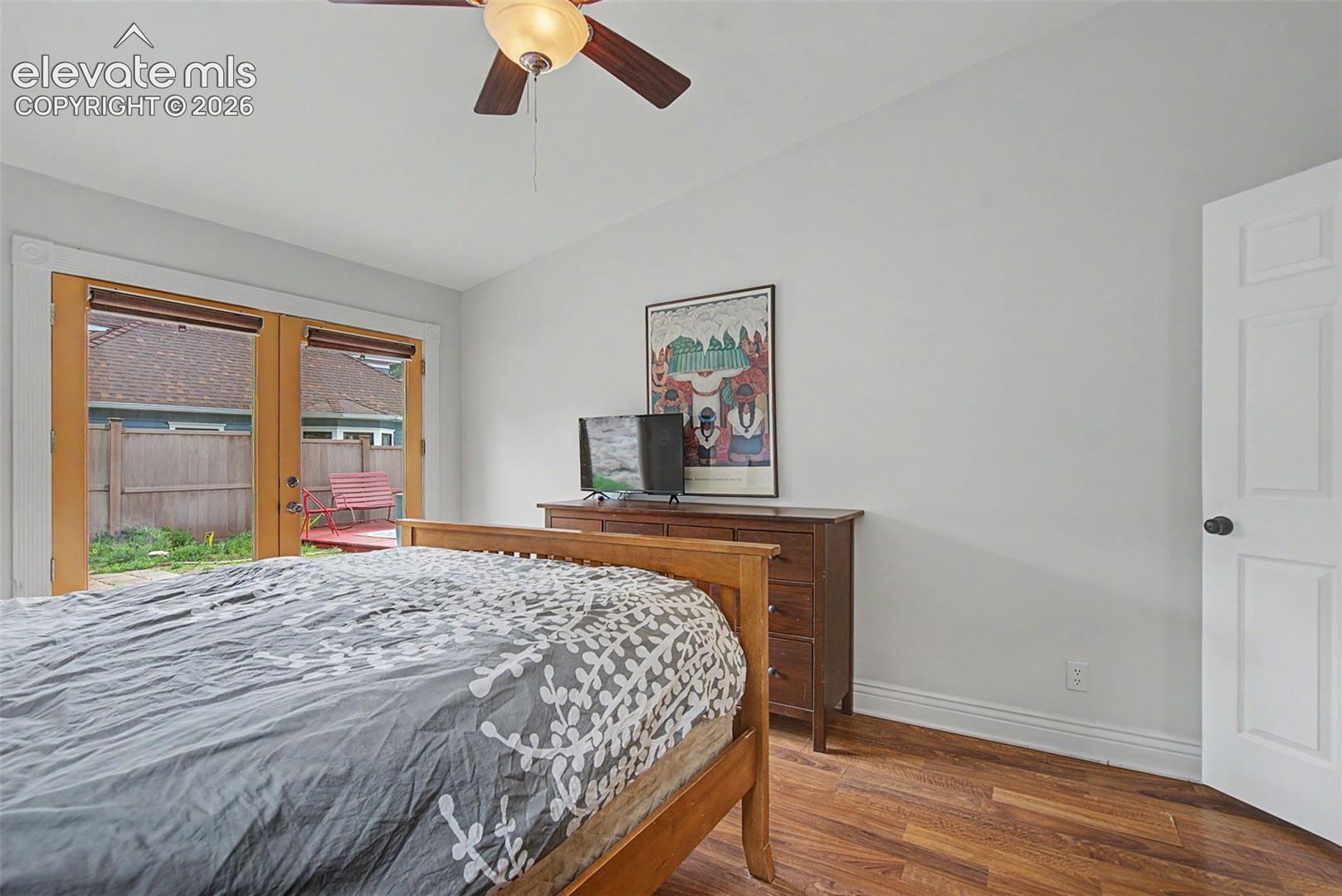Primary bedroom featuring hardwood flooring and double doors that leads out to the yard.