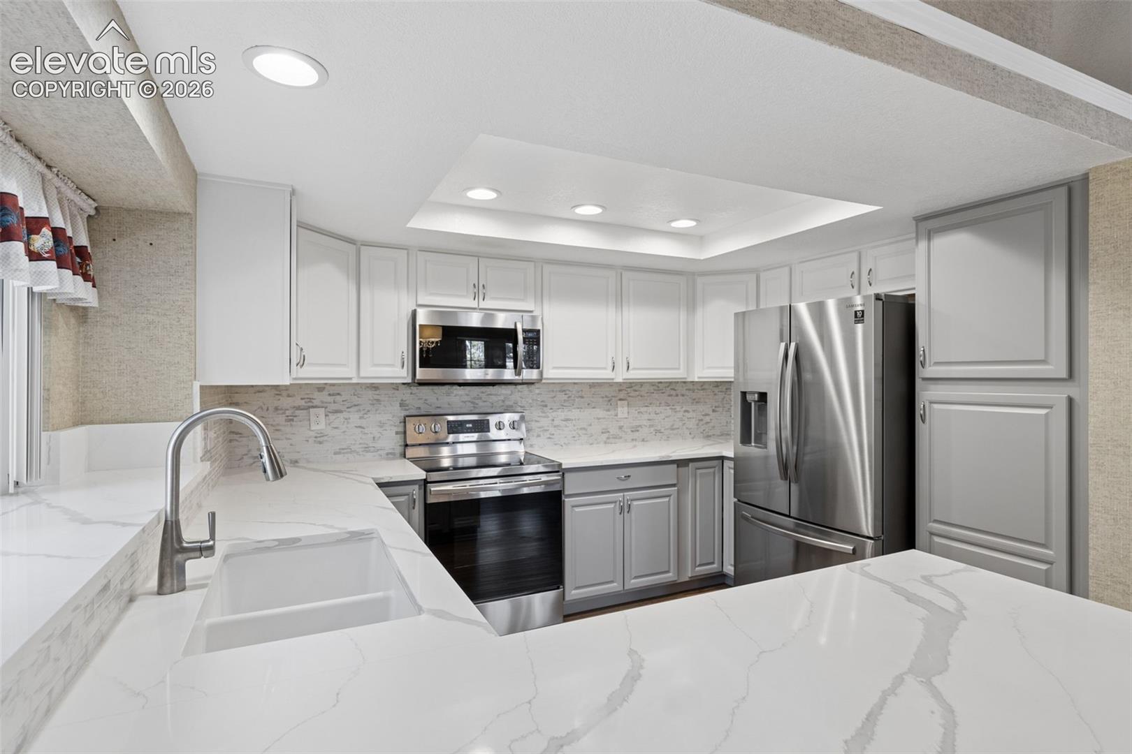 Kitchen featuring white cabinetry, stone-finish countertops, stainless steel appliances, recessed ceiling lighting, and a neutral-toned tile backsplash