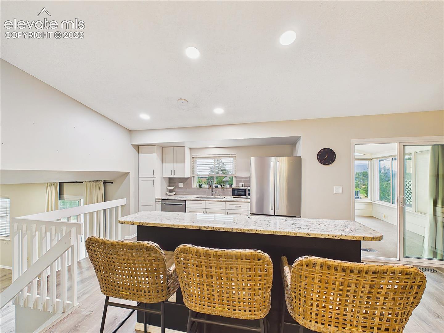 Large granite-topped breakfast bar offers comfortable seating, generous workspace, and a welcoming centerpiece for casual dining.