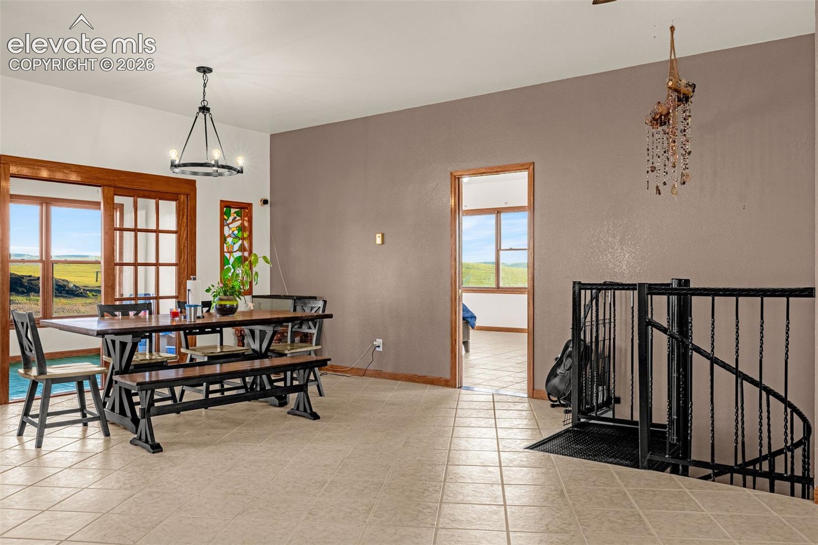Tiled flooring throughout, wood-framed sliding glass doors, built-in stained glass accent panel, open doorway with wood trim, and a black wrought iron spiral staircase