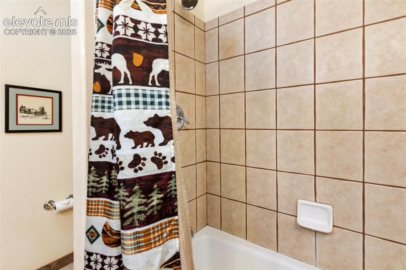 Tub and shower combination with light-toned square wall tiles and a chrome shower fixture