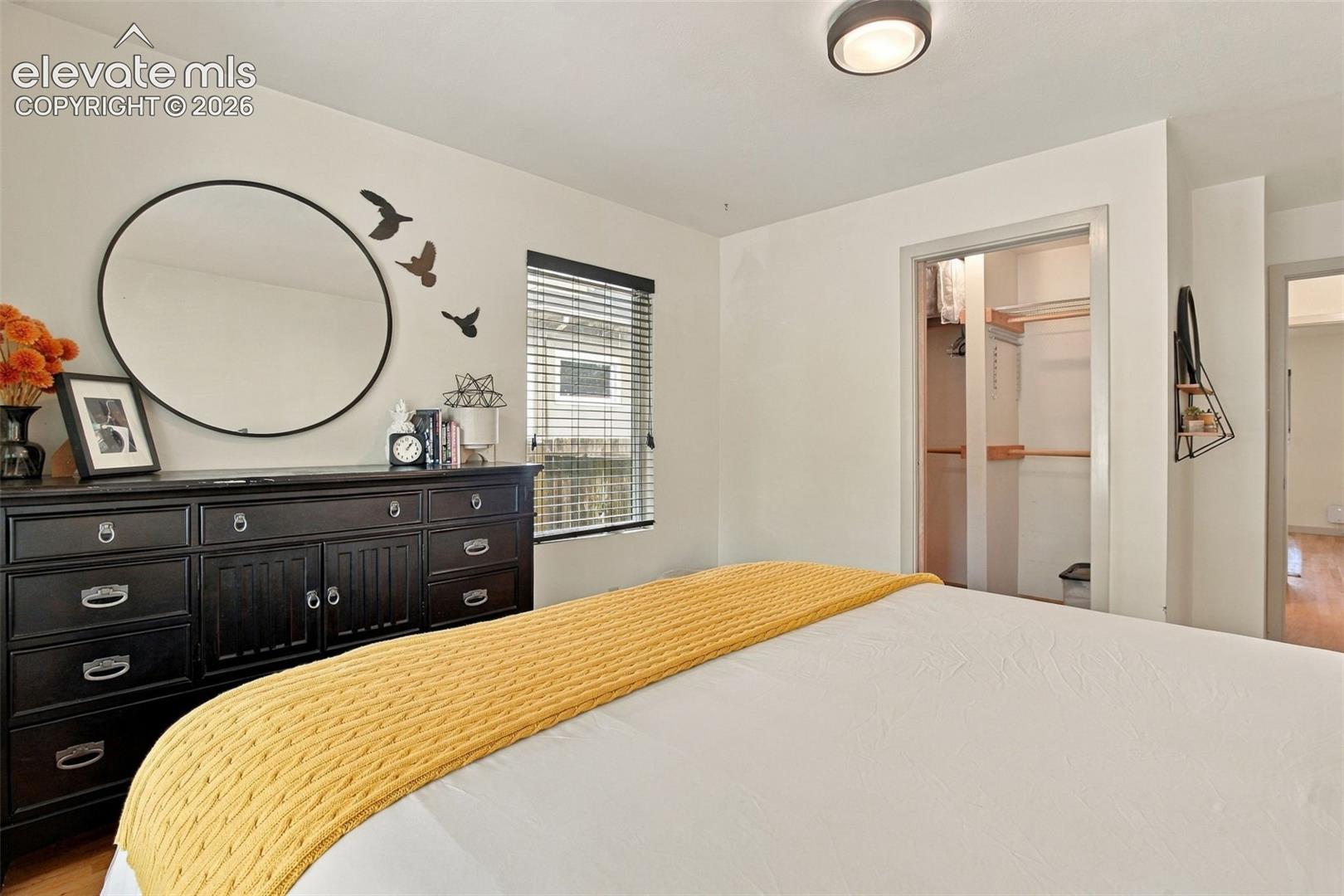 Interior space featuring neutral wall tones, a recessed ceiling light fixture, a window with horizontal blinds, and a walk-in closet with built-in shelving