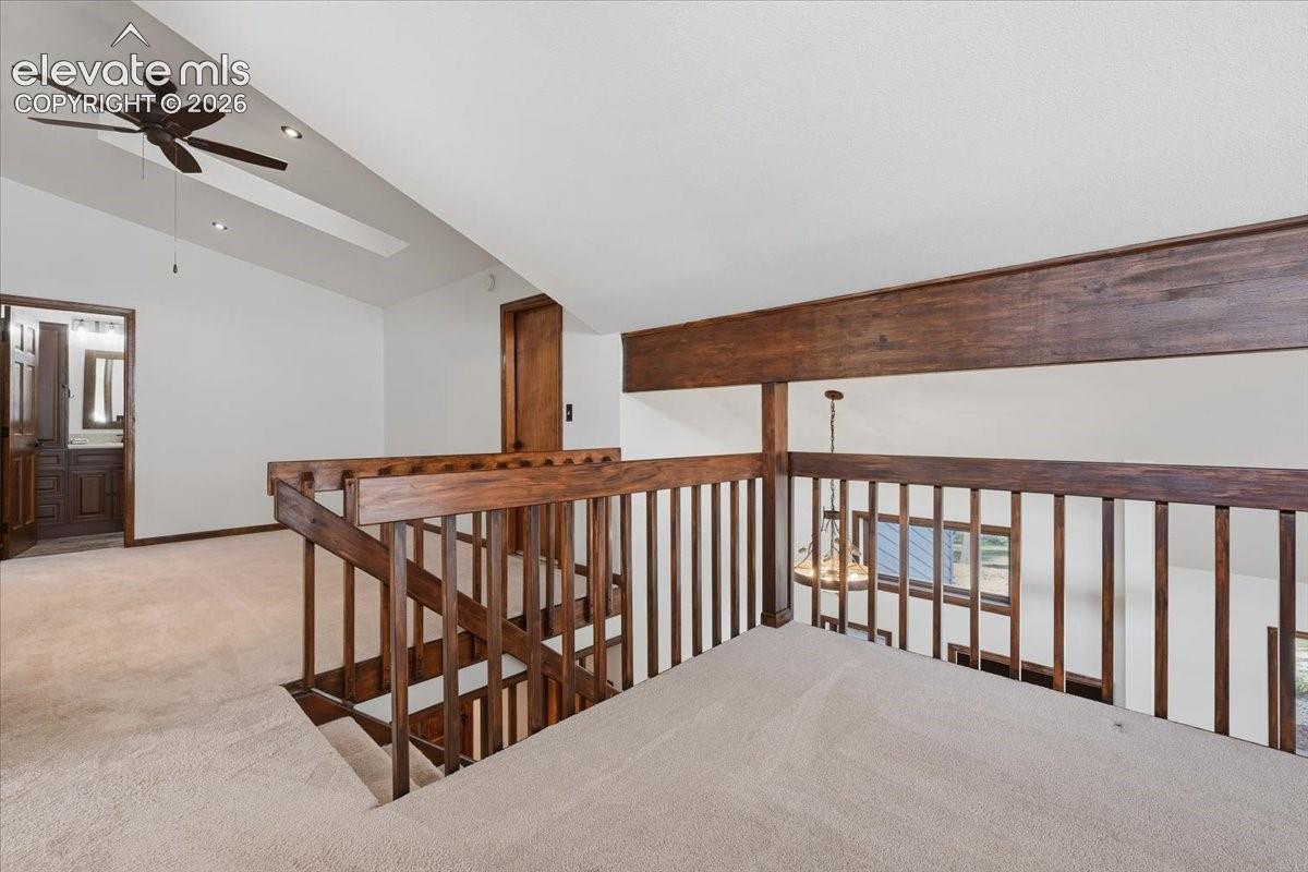 Carpeted loft area featuring wood railings, vaulted ceiling, ceiling fan, and recessed lighting