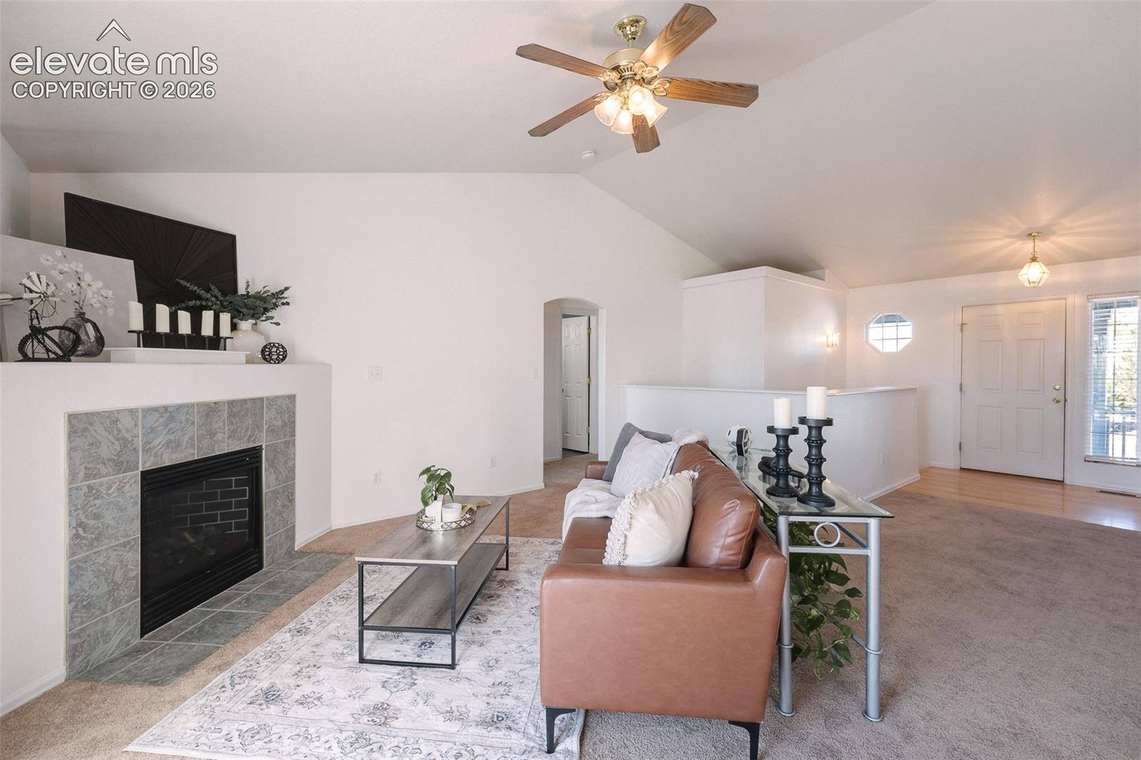 Soaring ceilings, abundant natural light, and a cozy fireplace create a living space that feels both open and inviting.