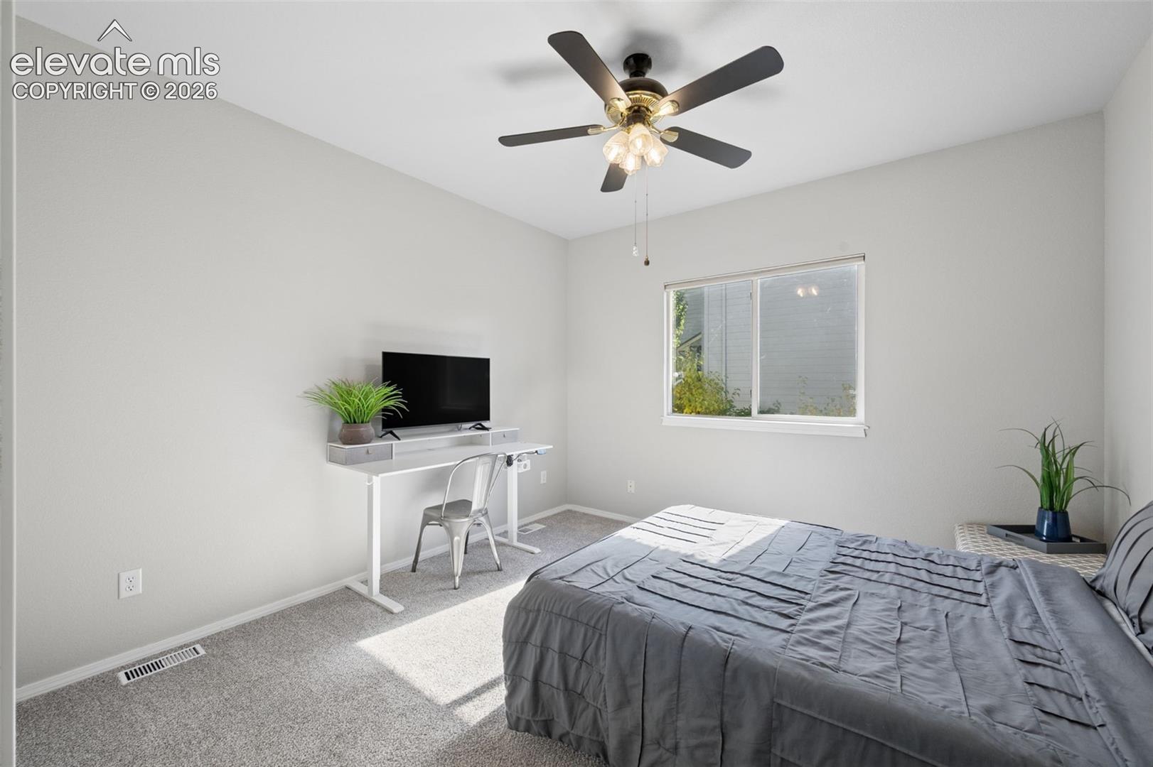 Neutral-toned interior room featuring wall-to-wall carpeting, a multi-light ceiling fan, and a horizontal sliding window