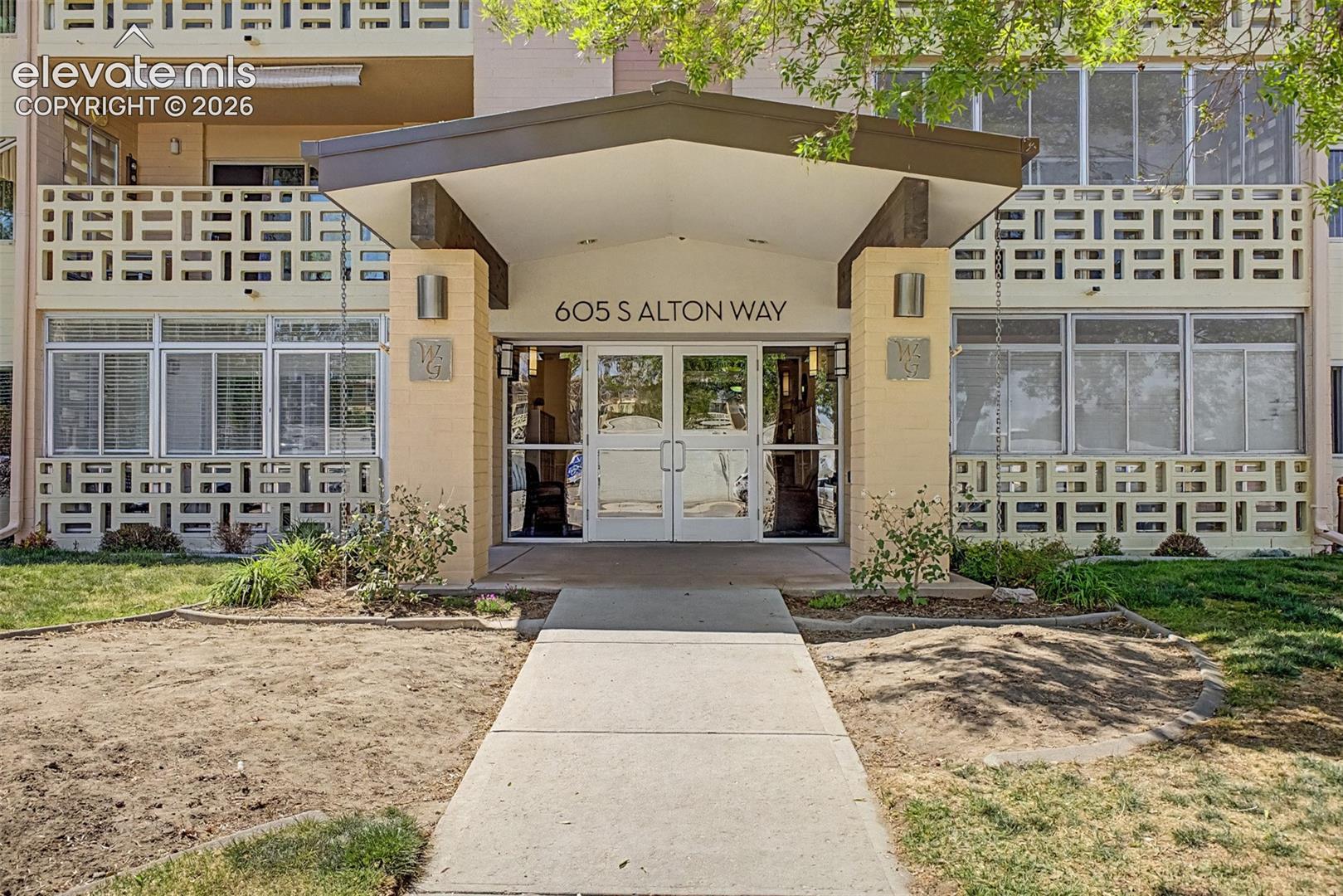 Building entrance featuring an overhead canopy, double glass doors, and exterior wall sconces