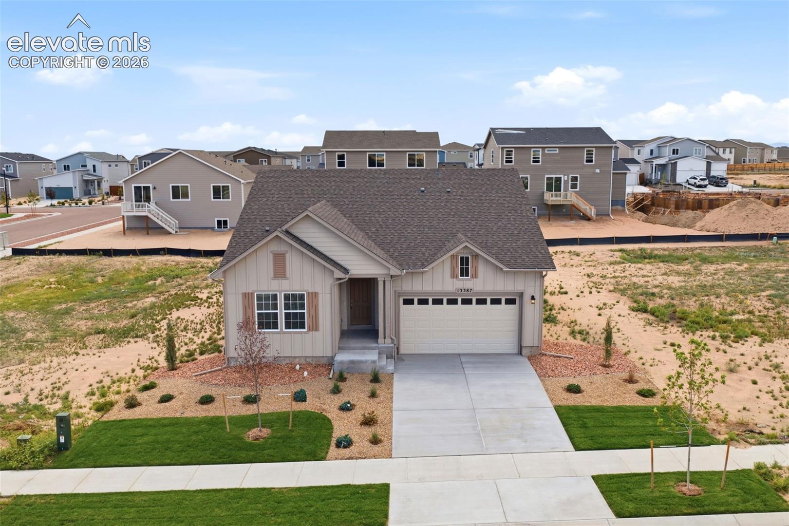 Single-story residence featuring vertical siding, a two-car garage with overhead windows, asphalt shingle roofing, and a concrete driveway