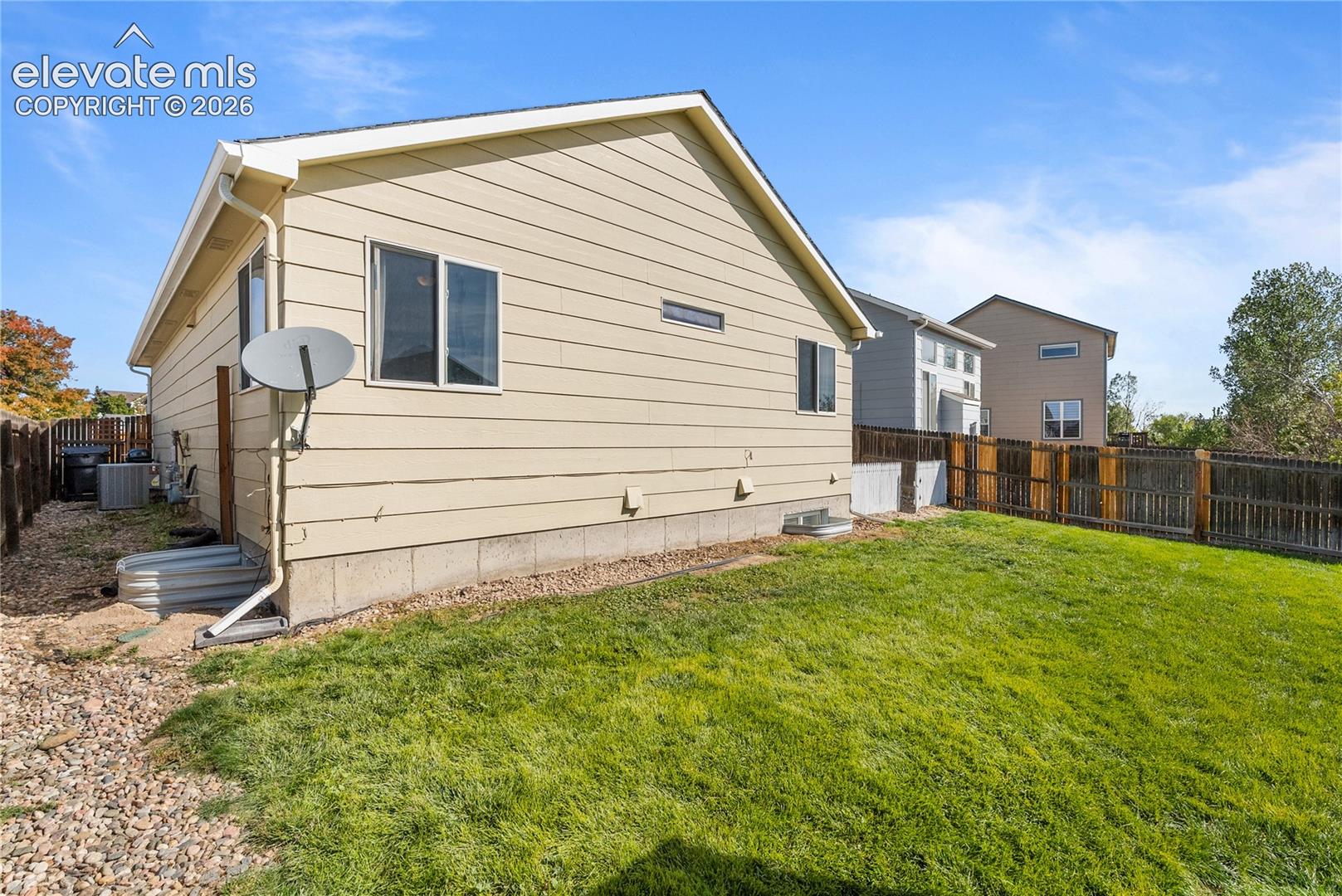Expansive backyard featuring a manicured lawn, full wood fencing, and a gravel-lined side yard