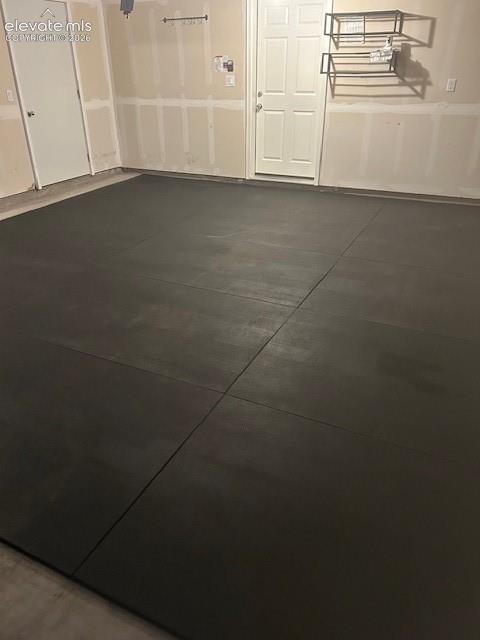 Insulated garage interior featuring dual six-panel doors, wall-mounted metal organizational shelving, and a large alcove for extra storage.