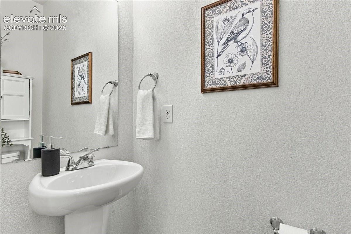 Pedestal sink with a polished chrome faucet, full-height wall mirror, and a wall-mounted towel ring