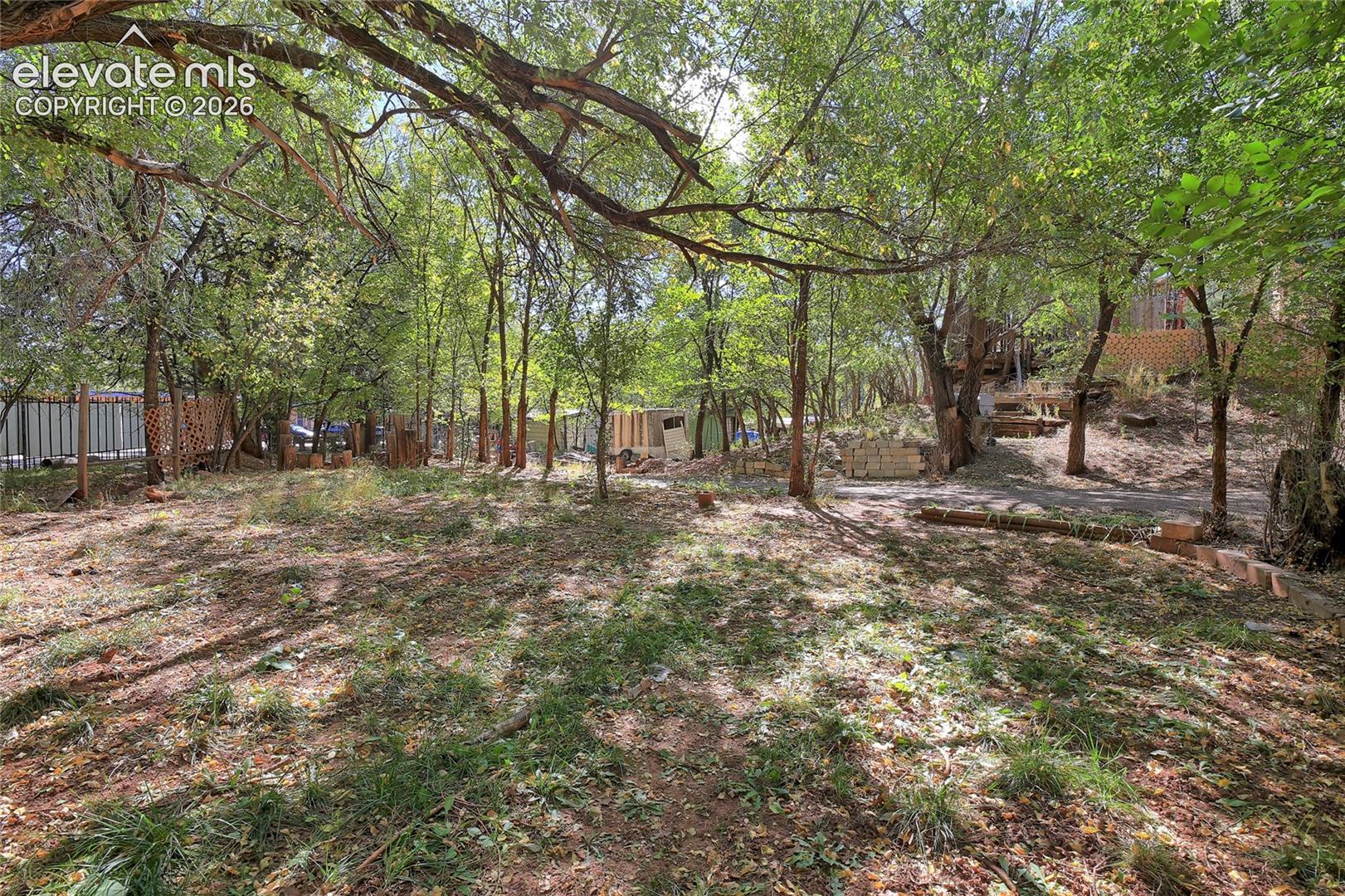 Expansive lot featuring mature trees, natural terrain, and perimeter fencing